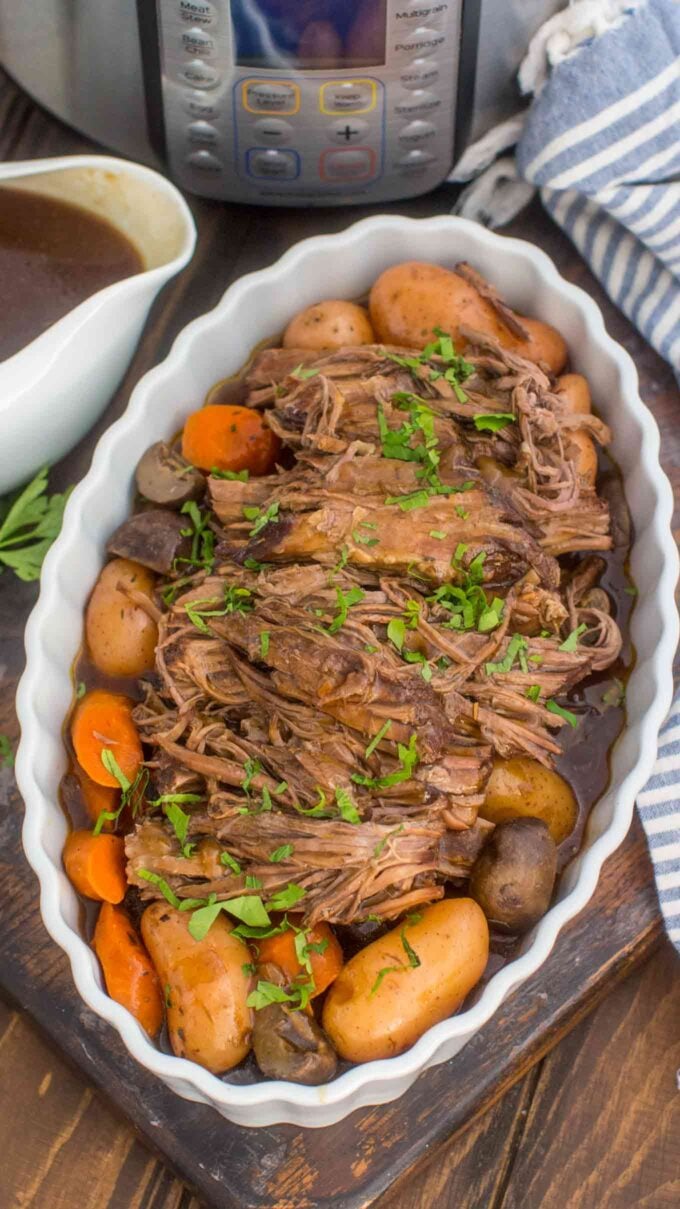 instant pot pot roast with vegetables in a casserole dish next to a pressure cooker