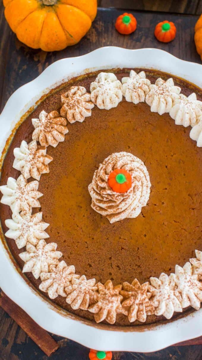 overhead shot of pumpkin pie without crust in a baking dish decorated with whipped cream and cinnamon 