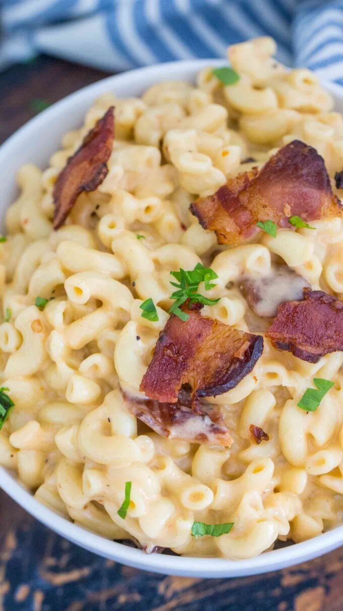 Picture of creamy mac and cheese topped with bacon on a white plate.