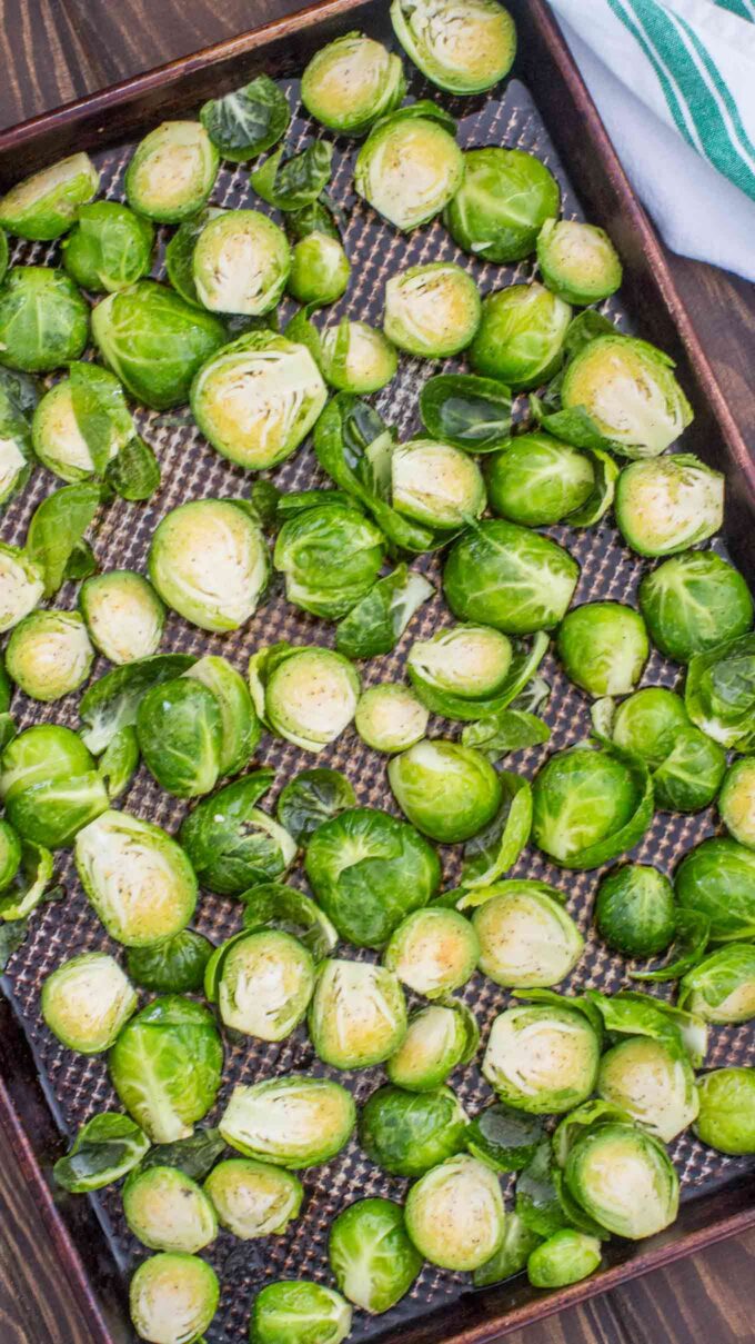 Raw Brussels sprouts cut in half and layered on a baking sheet 