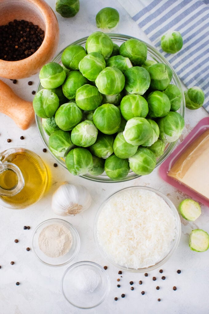 Overhead shot of crispy roasted Brussels sprouts ingredients in bowls on a table.