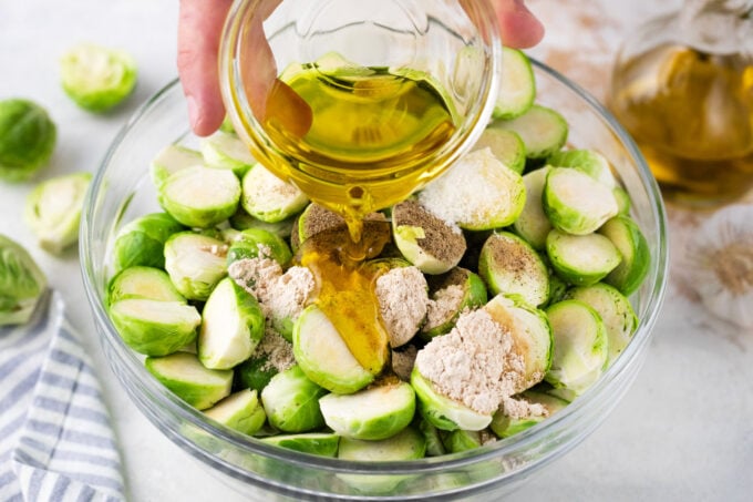 Seasoning Brussels sprouts in a bowl.