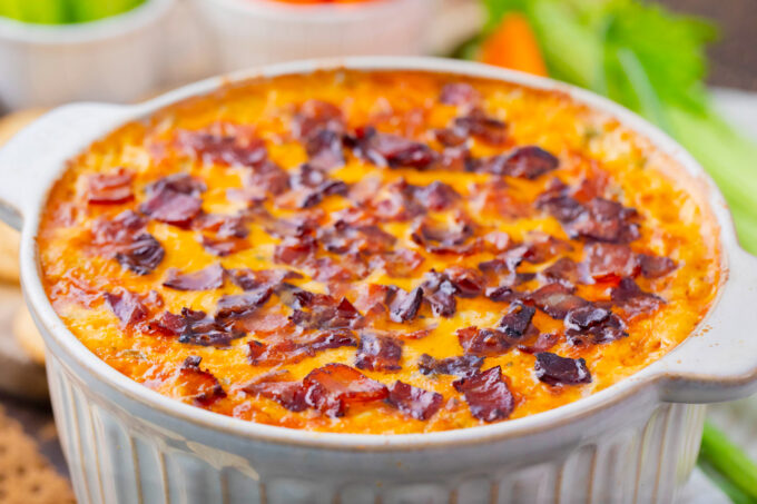 Baked Buffalo crack chicken dip topped with crispy bacon.
