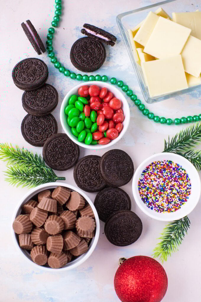 Overhead shot of Christmas Oreo ornaments ingredients arranged on a white surface.