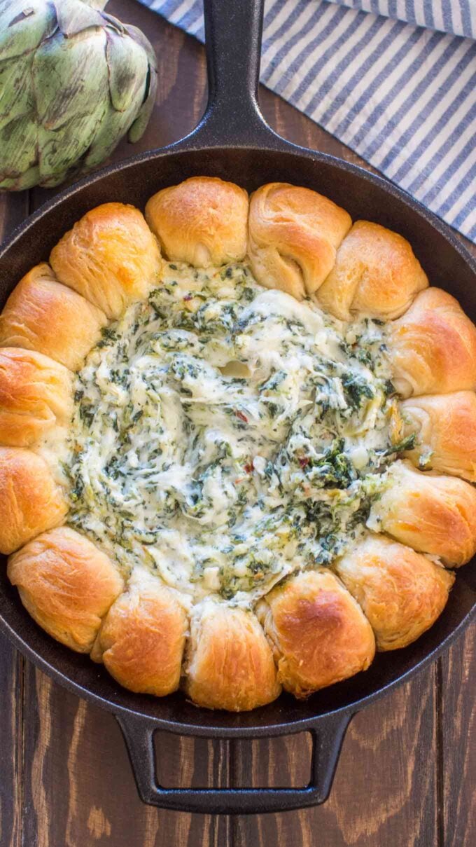 Spinach Artichoke Dip is super gooey and cheesy, surrounded by biscuit rolls, all baked in one skillet. Loaded with spinach, marinated artichokes, and cheeses, it is the perfect bubbly and creamy appetizer. #appetizer #dip #easyrecipe #partyfood #cheese #cheesedip #spinachdip #sweetandsavorymeals #vegetarian