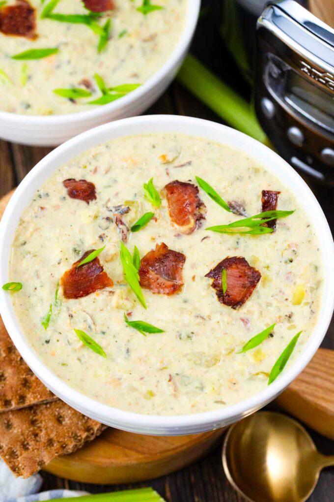 two bowls of crockpot clam chowder topped with bacon