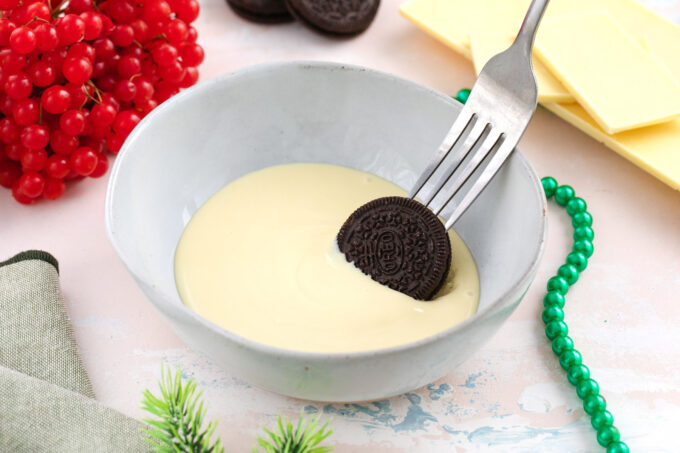 Dipping an Oreo cookie in white chocolate.
