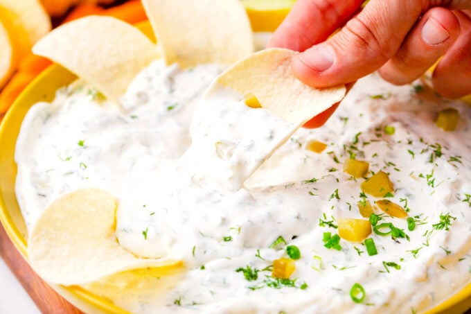 Dipping potato chips in dill pickle dip.