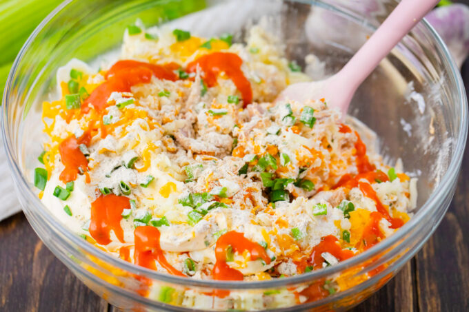 Stirring Buffalo crack chicken dip ingredients in a bowl.
