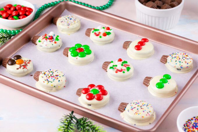 Festive Christmas Oreo ornaments arranged on a cookie sheet.