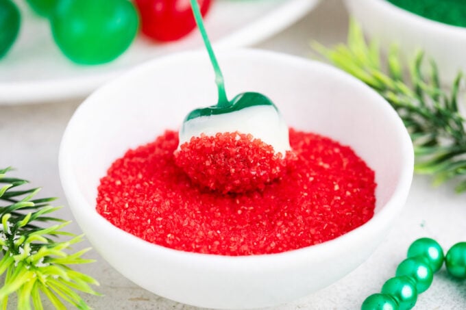 Tossing a white chocolate covered green Maraschino cherry in red sanding sugar.