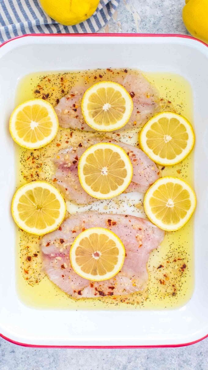 tilapia filets in a baking pan topped with lemon rounds