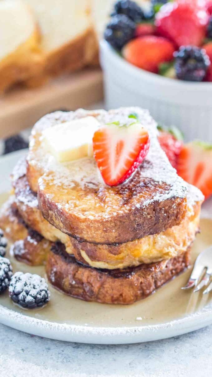 Image of homemade brioche French toasts topped with butter and sliced strawberry.