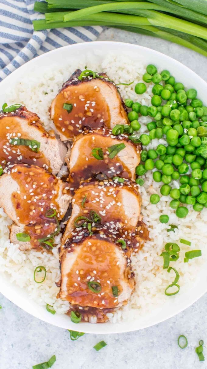 Cooked and sliced pork tenderloin with green peas over white rice
