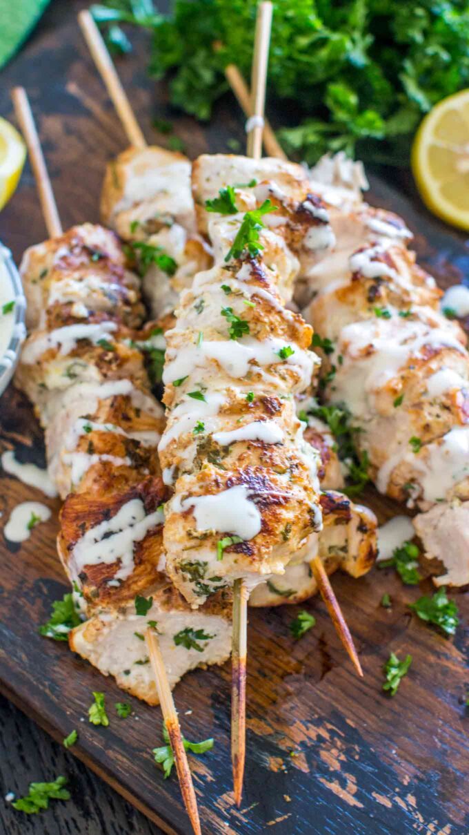 Keto Italian Chicken Skewers drizzled with white sauce on a serving board