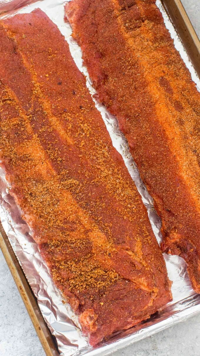 Photo of pork ribs with homemade dry rub on a baking sheet.