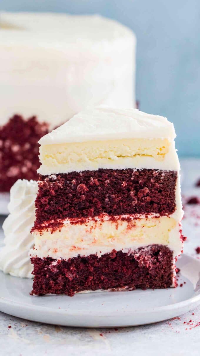 a slice of homemade Red Velvet Cake Cheesecake Cheesecake Factory Copycat cake served with whipped cream