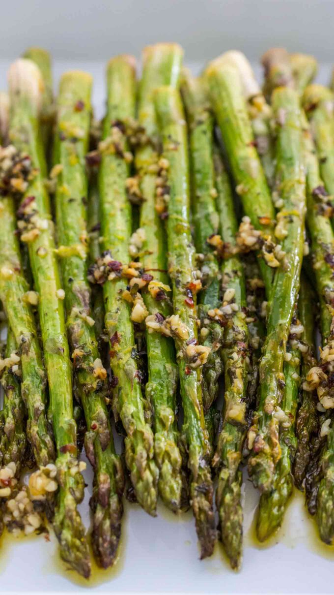 Roasted asparagus garnished with garlic on a white plate