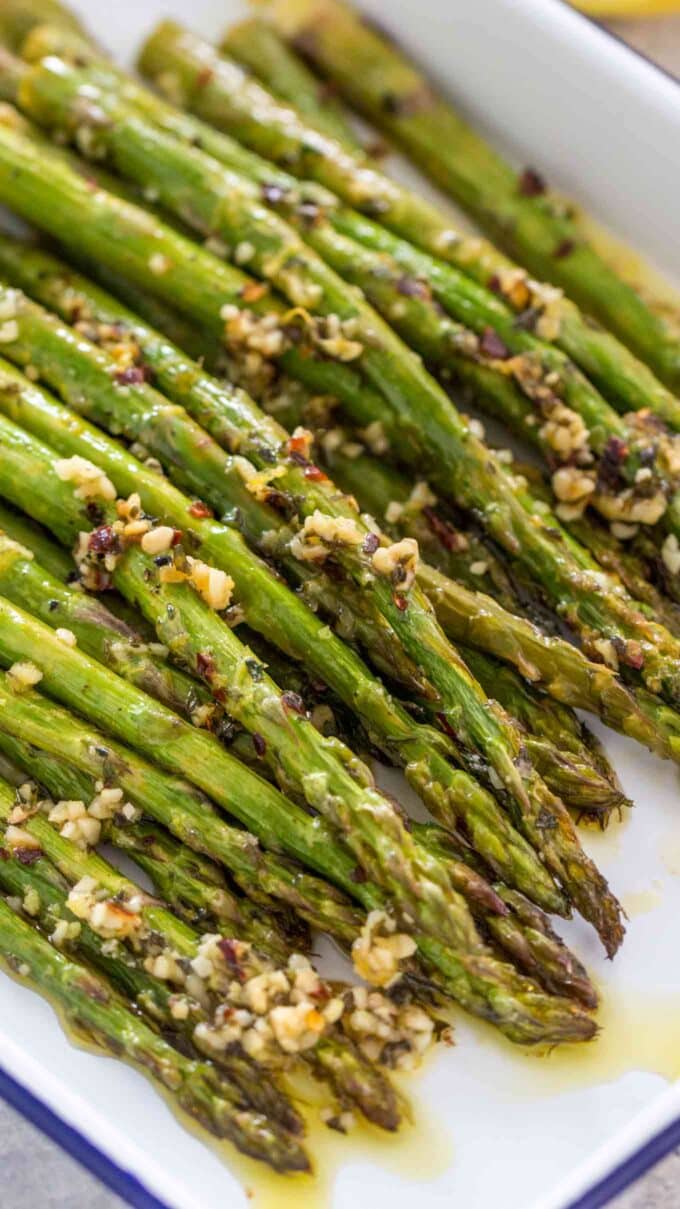 Oven-baked asparagus topped with garlic on a white dish