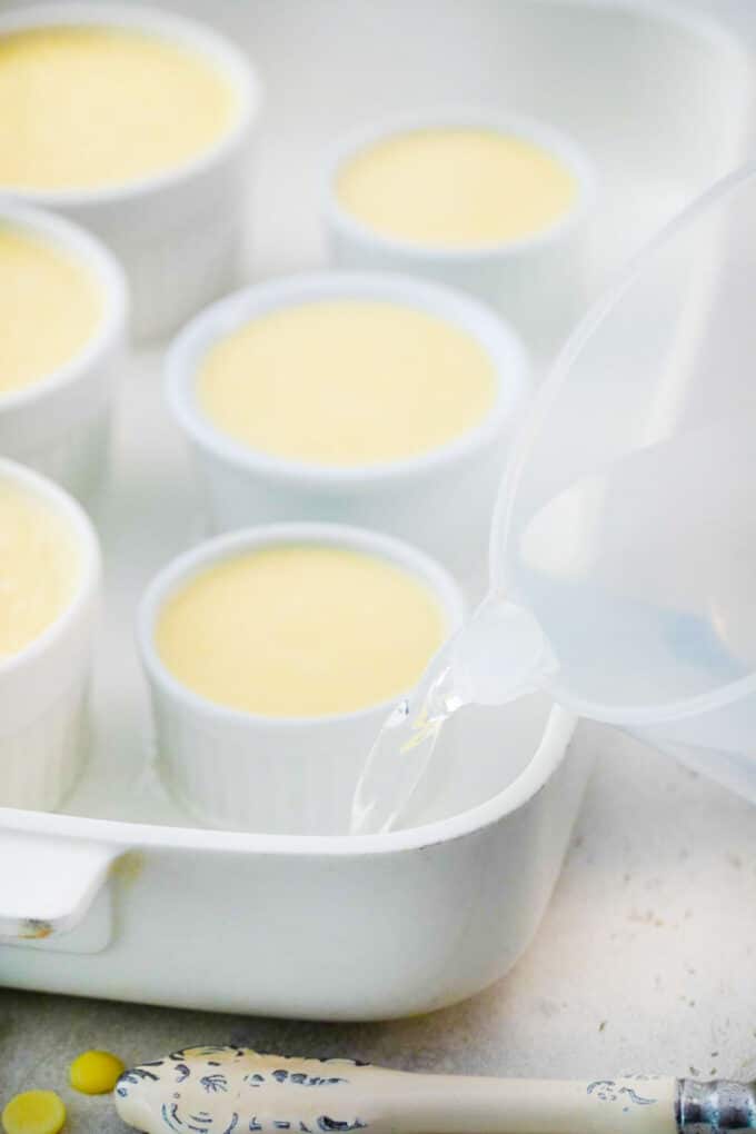 pouring water into a casserole dish with creme brulee ramekins