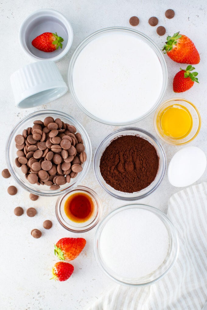 Overhead shot of chocolate creme brulee ingredients in bowls on a table.