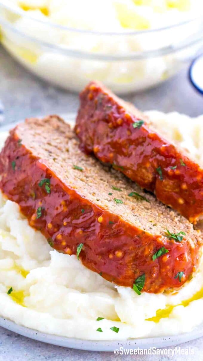 two homemade meatloaf slices on top of a plate with mashed potatoes