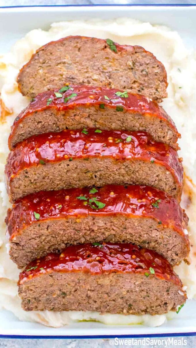 beef meatloaf in a tray on top of mashed potatoes