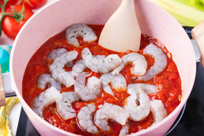 Adding shrimp to Creole tomato sauce.