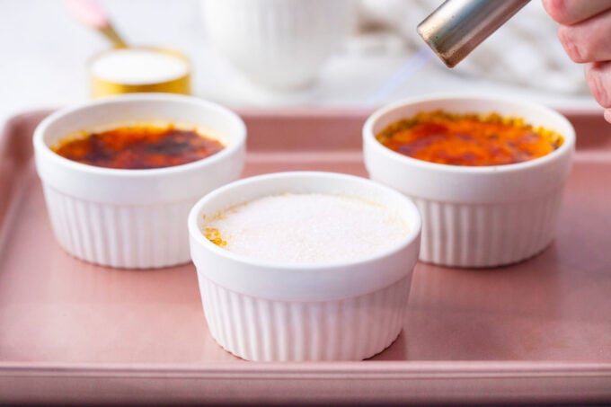 Crisping the tops of homemade creme brulee with a blowtorch.