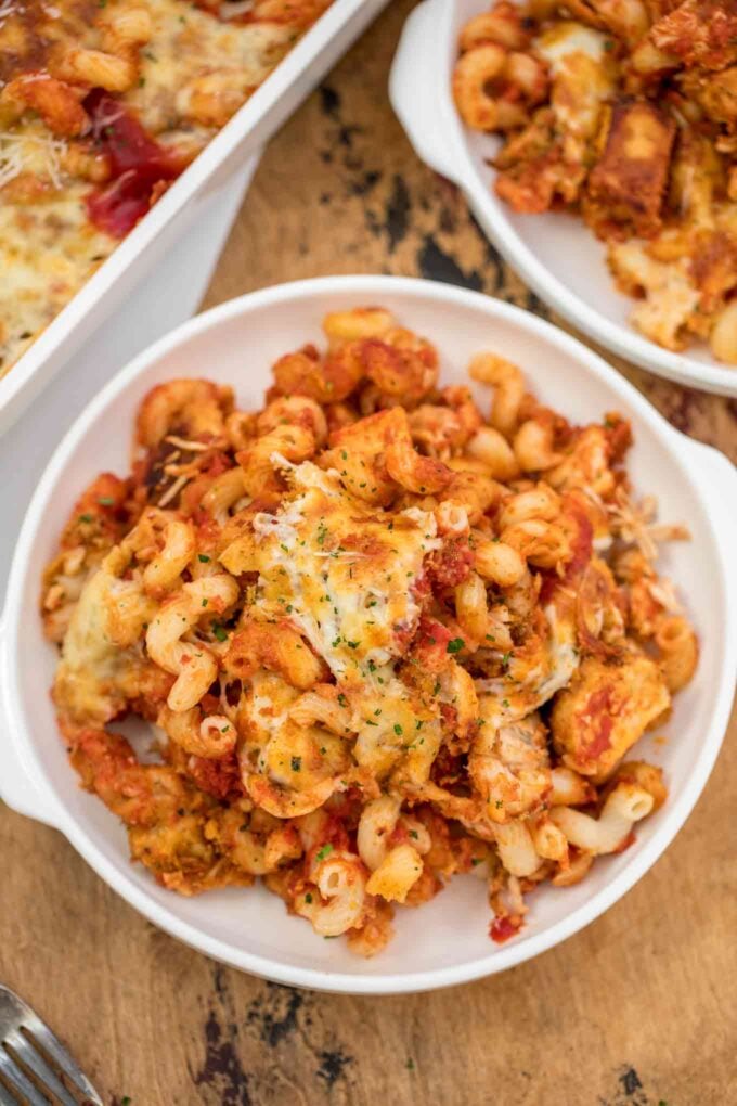 Homemade chicken parmesan and pasta on a white plate. 