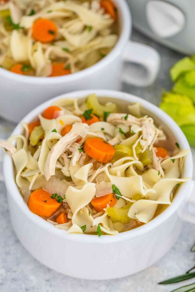 Homemade chicken noodle soup made with chicken breasts and veggies in a white bowl