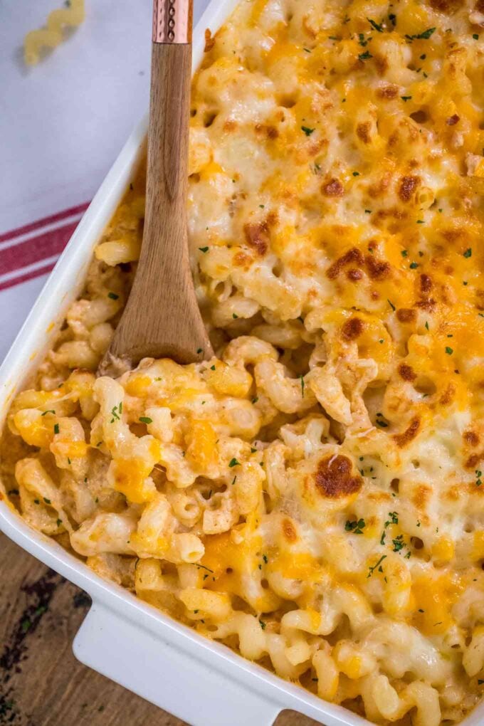 Gluten free mac and cheese casserole with a wooden spoon inside.