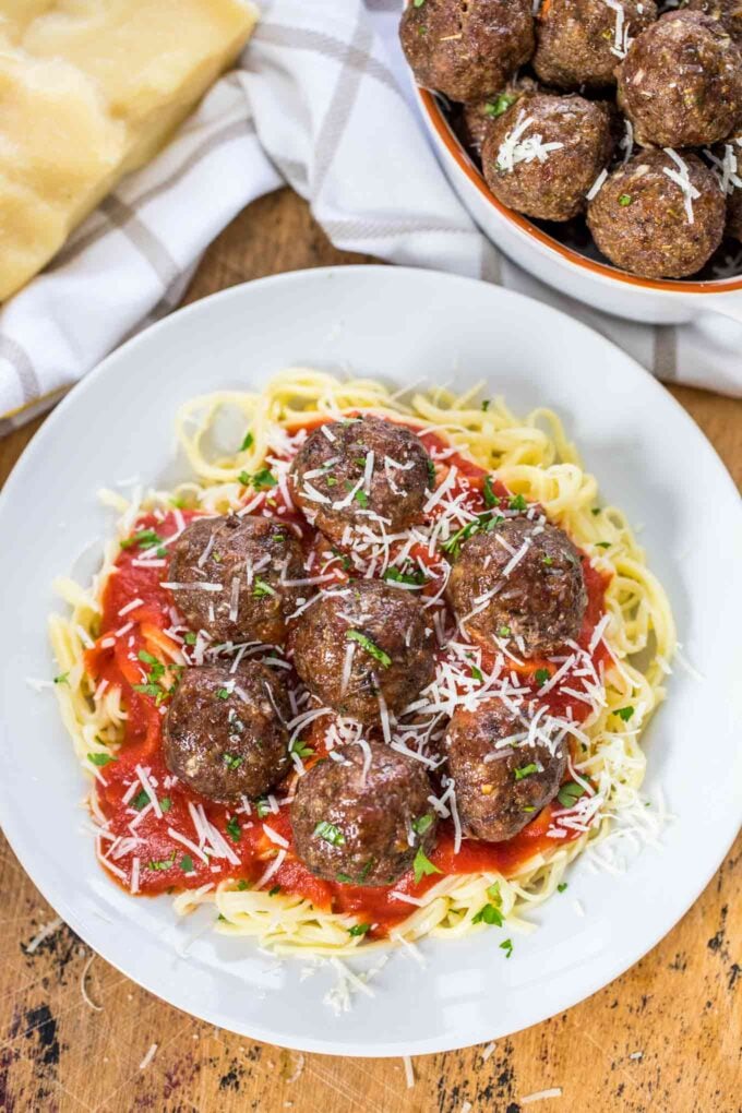 Best homemade meatballs over pasta and red marinara sauce sprinkled with Parmesan cheese