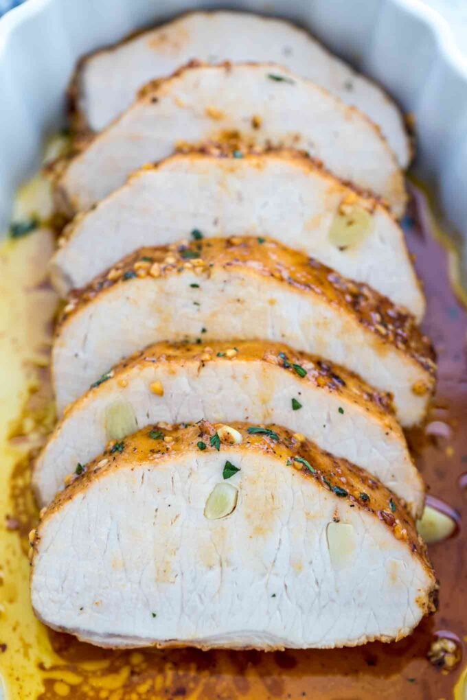 slices of baked garlic pork loin with spices in a baking dish