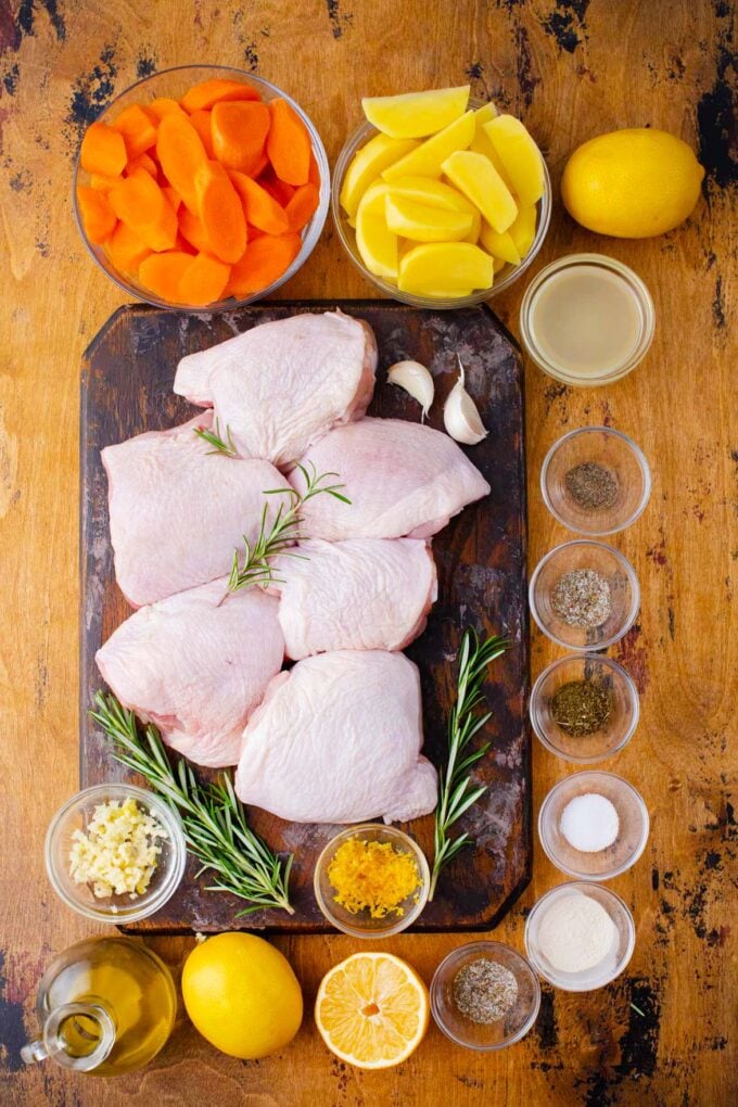 Overhead shot of Italian chicken and potatoes ingredients arranged on a wooden table.