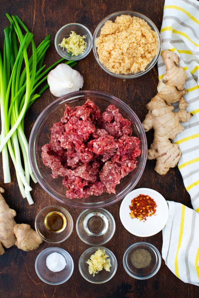 Overhead shot of Korean ground beef ingredients in bowls on a wooden table.