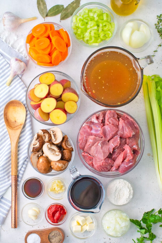 Overhead shot of homemade beef stew ingredients in bowls on a table.