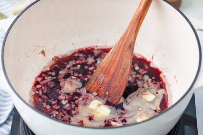 Deglazing a Dutch oven with red wine.