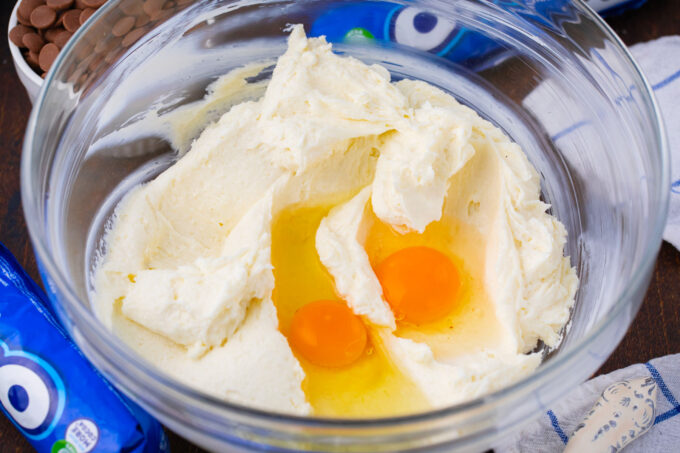 Adding eggs to cheesecake filling.
