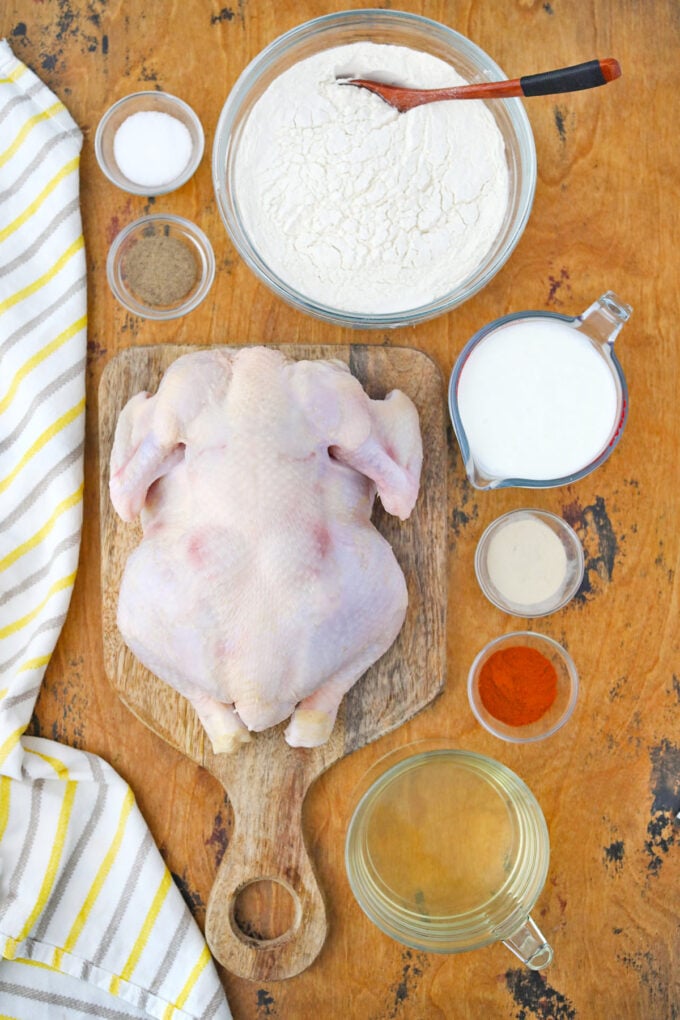 Overhead shot of homemade fried chicken ingredients on a wooden table.