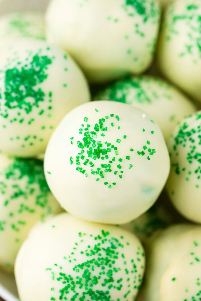 Homemade mint chocolate chip truffles covered in white chocolate and topped with green sanding sugar.
