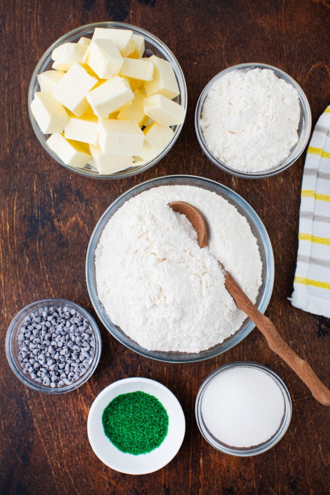 Overhead shot of mint chocolate chip truffles ingredients in bowls on a wooden surface.