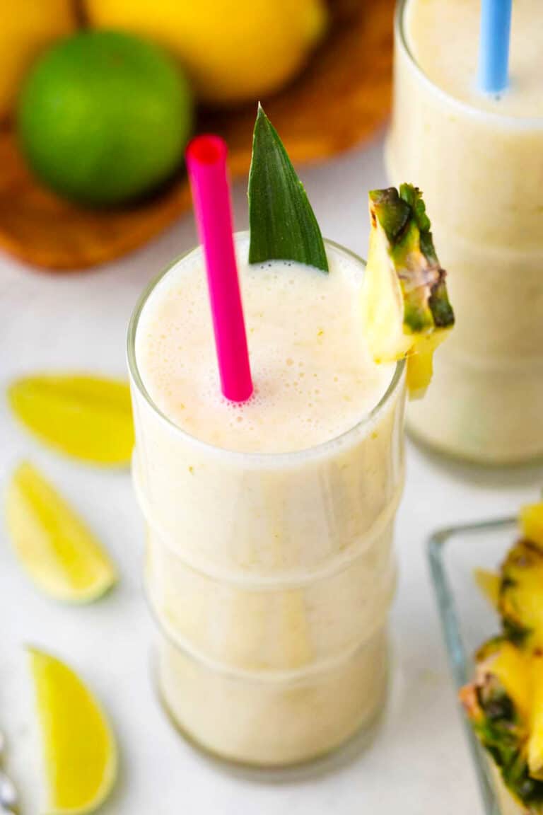 pineapple smoothie with lime wedges next to it