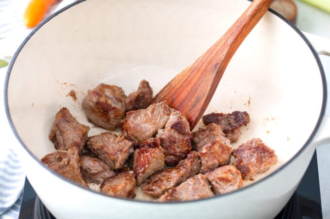Searing beef pieces in a Dutch oven.