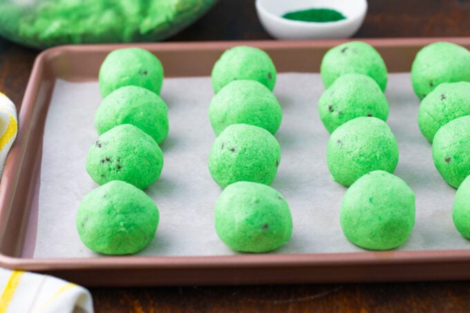Rolled mint chocolate chip truffles arranged on a baking sheet.