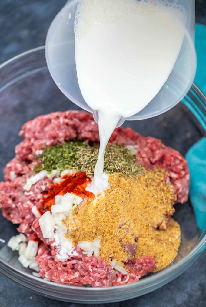 adding milk to ground beef, chopped onions, and herbs in a large bowl.