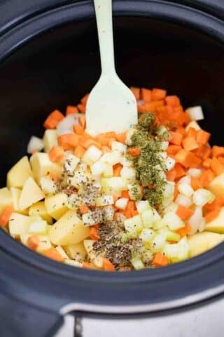 potatoes carrots onion and dried herbs in a crockpot