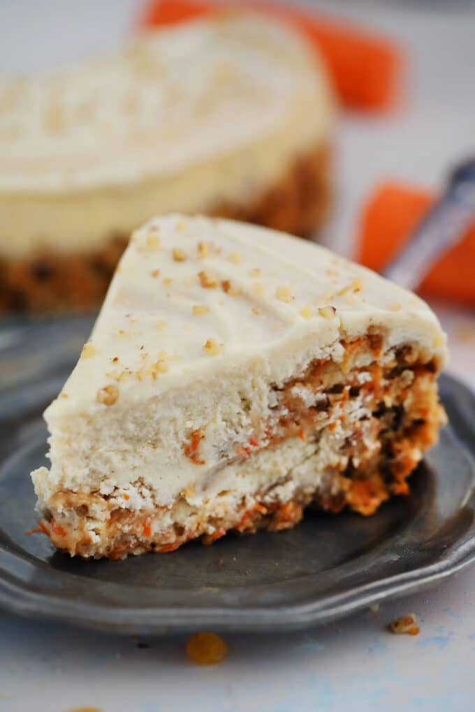 Photo of a slice of carrot cake cheesecake on a silver plate. 