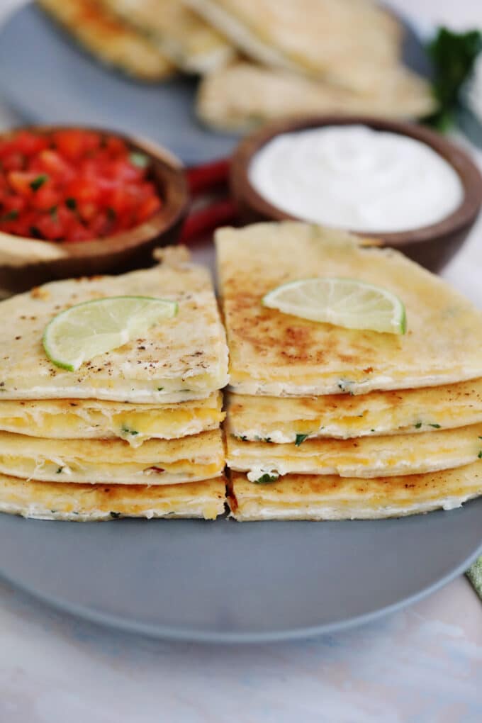 Best cheese quesadilla garnished with lime next to salsa and sour cream on a plate