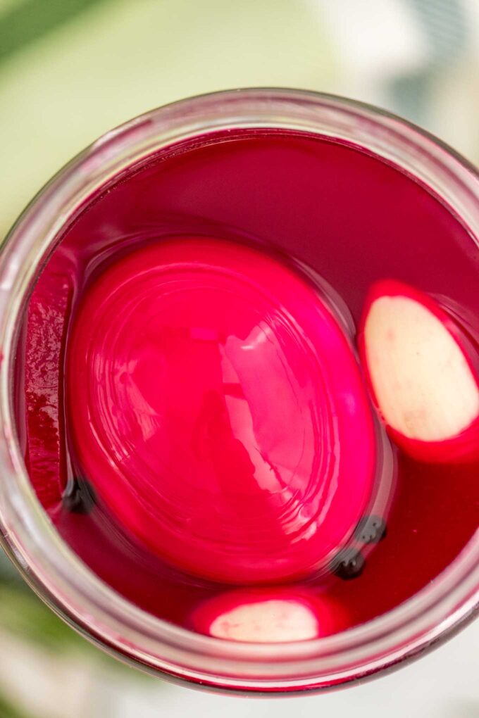 Pickled eggs with beets and garlic cloves in a glass jar